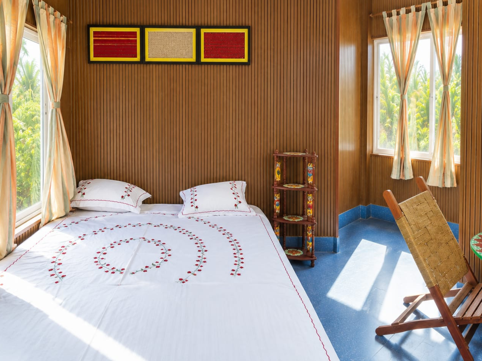 Economy Room with a king size bed, embroidered white linen, wood-panelled walls and windows onto the trees