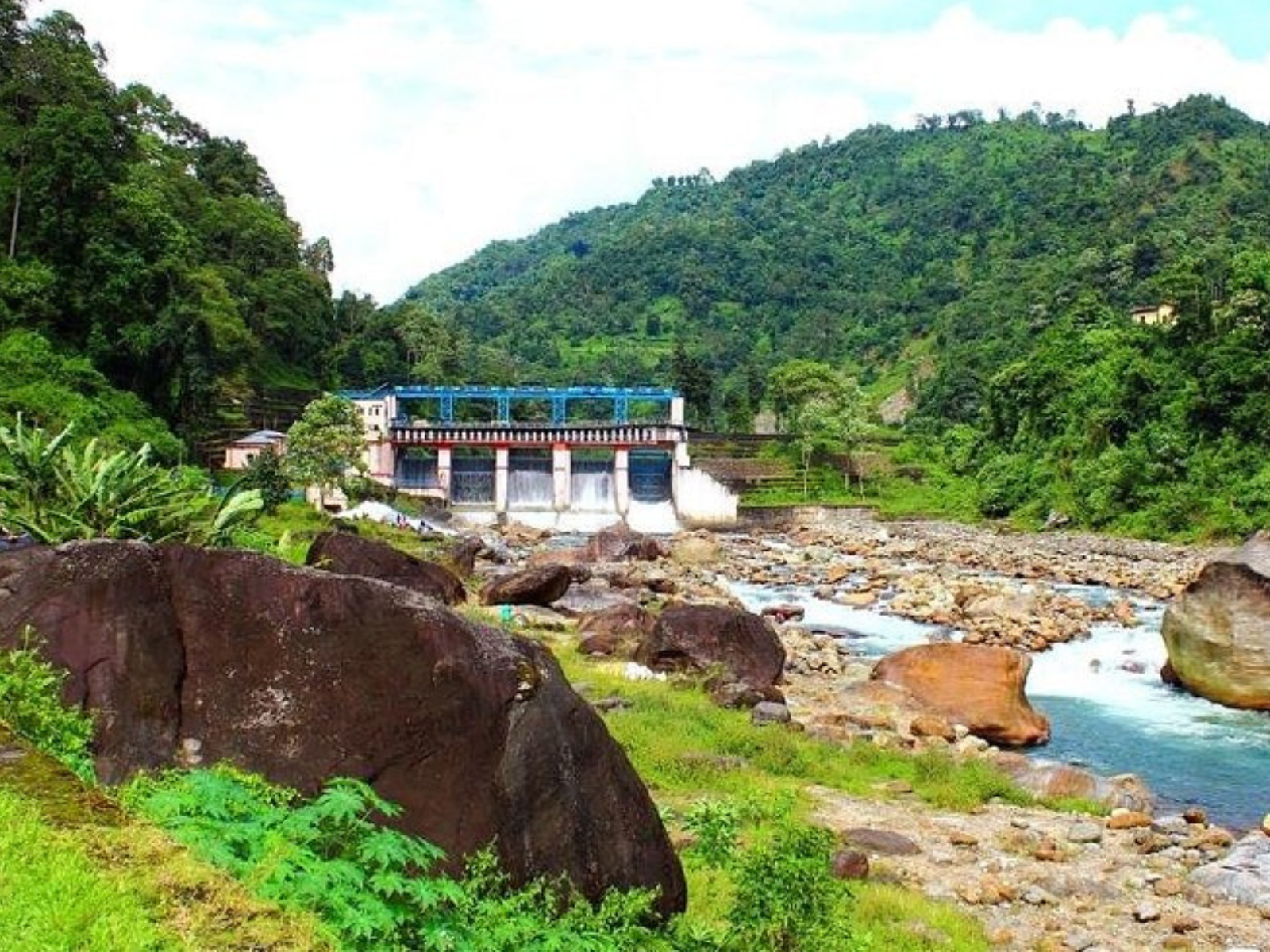The Jaldhaka barrage at Bindu with water rushing into a boulder-strewn river below green hills