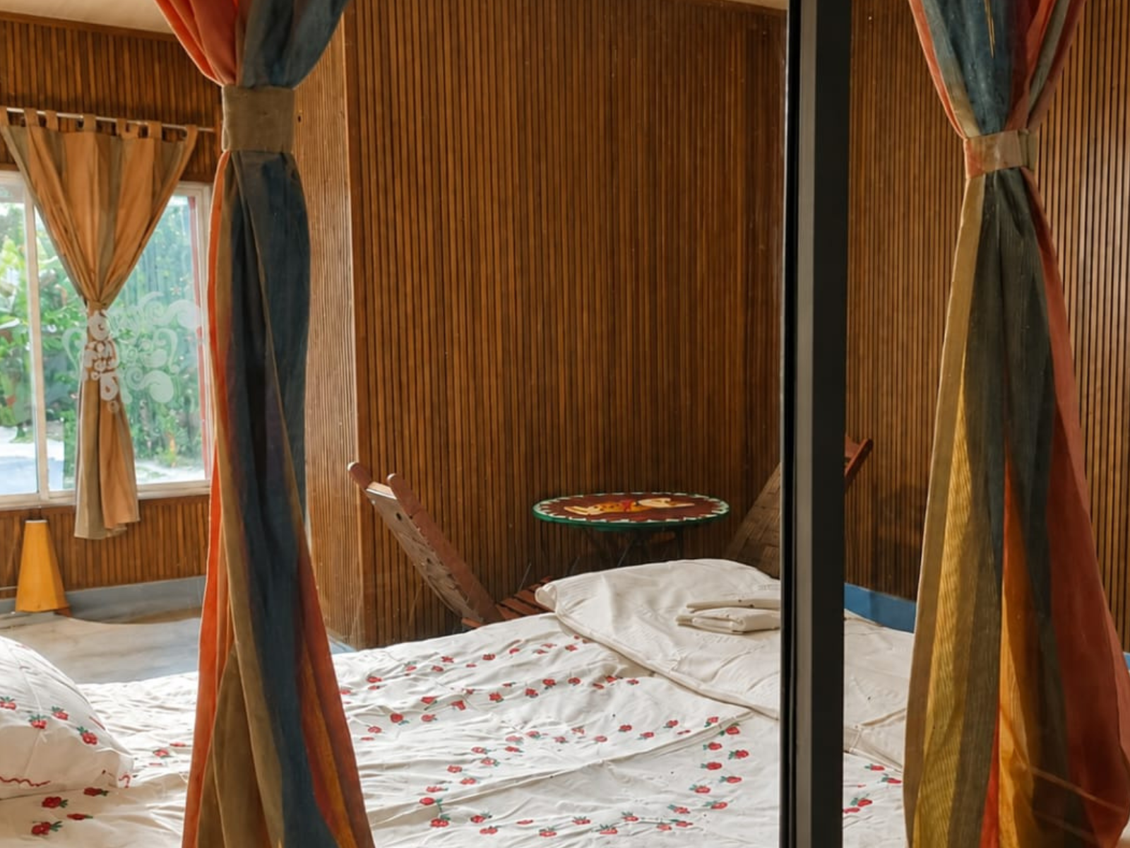 Bed with embroidered linen and coloured drapes in the Economy Room