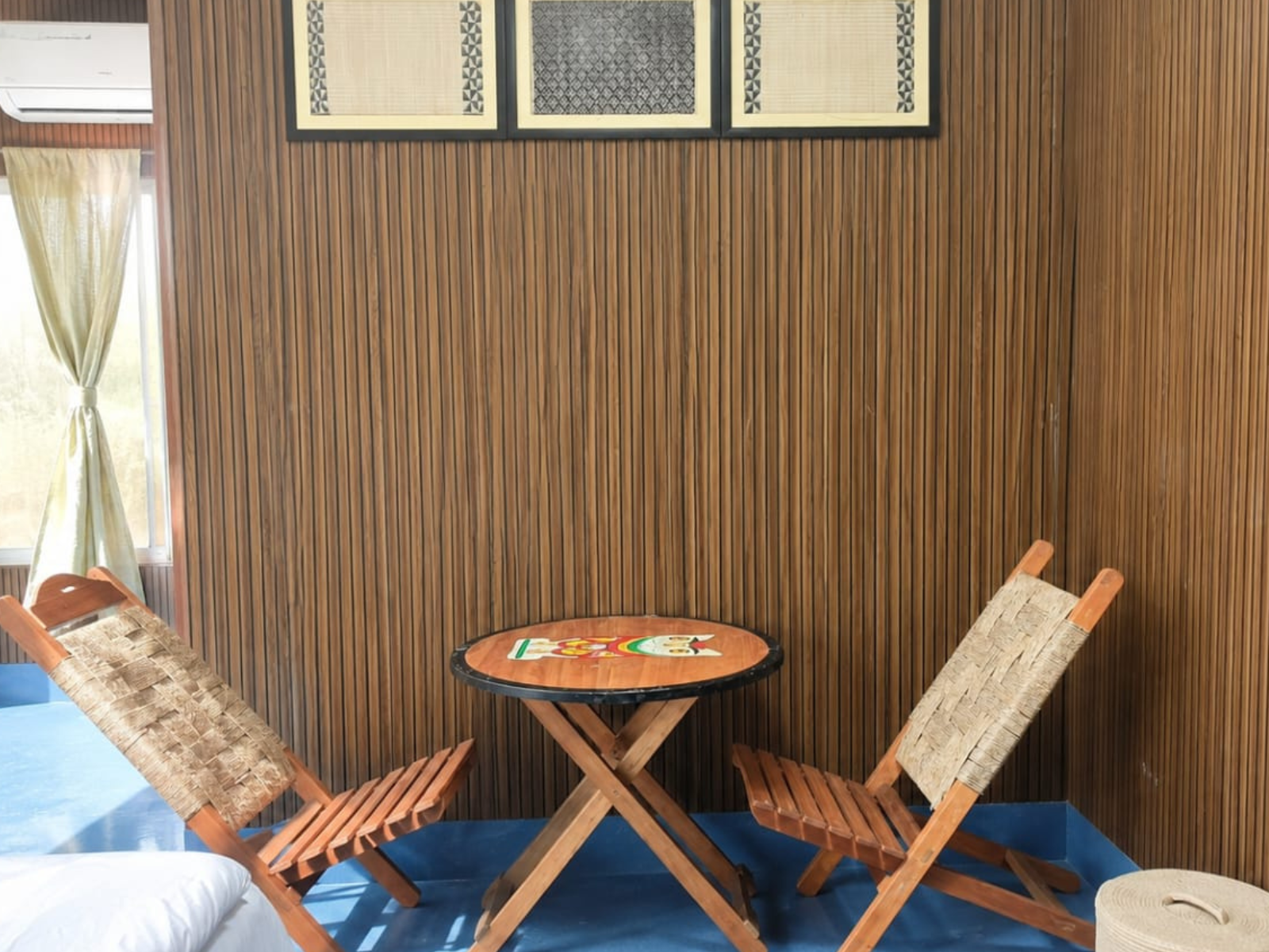 Cane folding chairs and a hand-painted table beside the window in the Economy Room