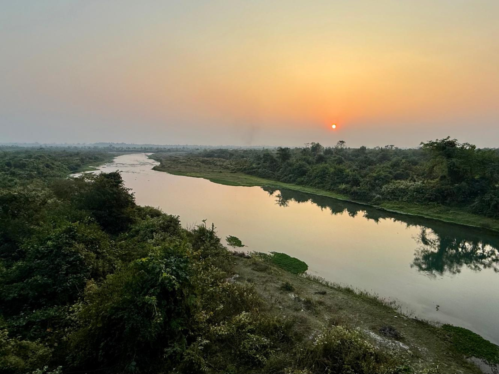 Sunset over a river winding through the Dooars floodplain, photographed by a guest