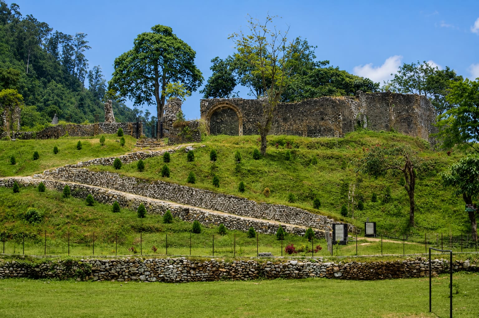 The stone ramparts and arched gateway of Buxa Fort on the ridge above Santalabari